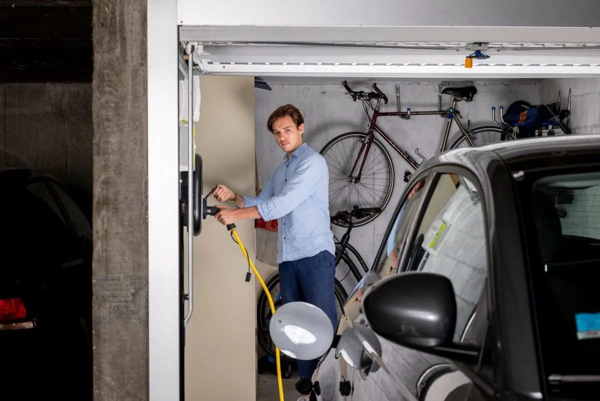 Personne chargeant sa voiture à partir de sa prise privée dans son garage