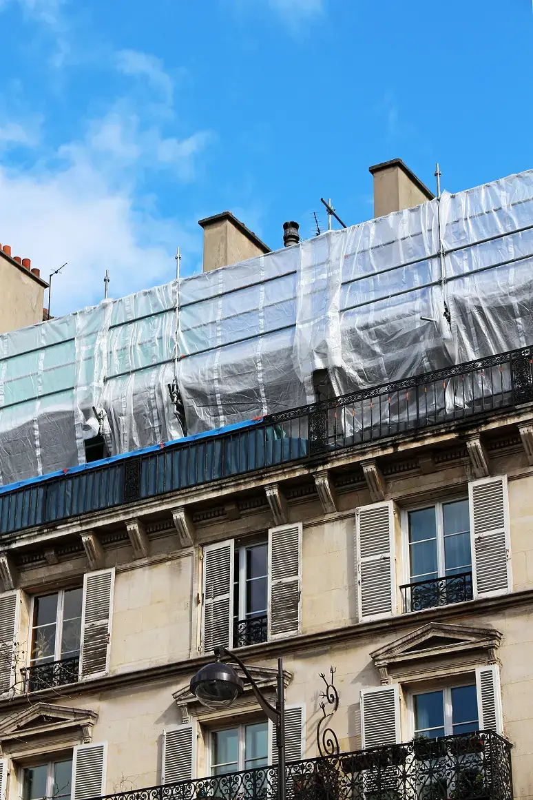 Image d'un immeuble en travaux, recouvert de bâches